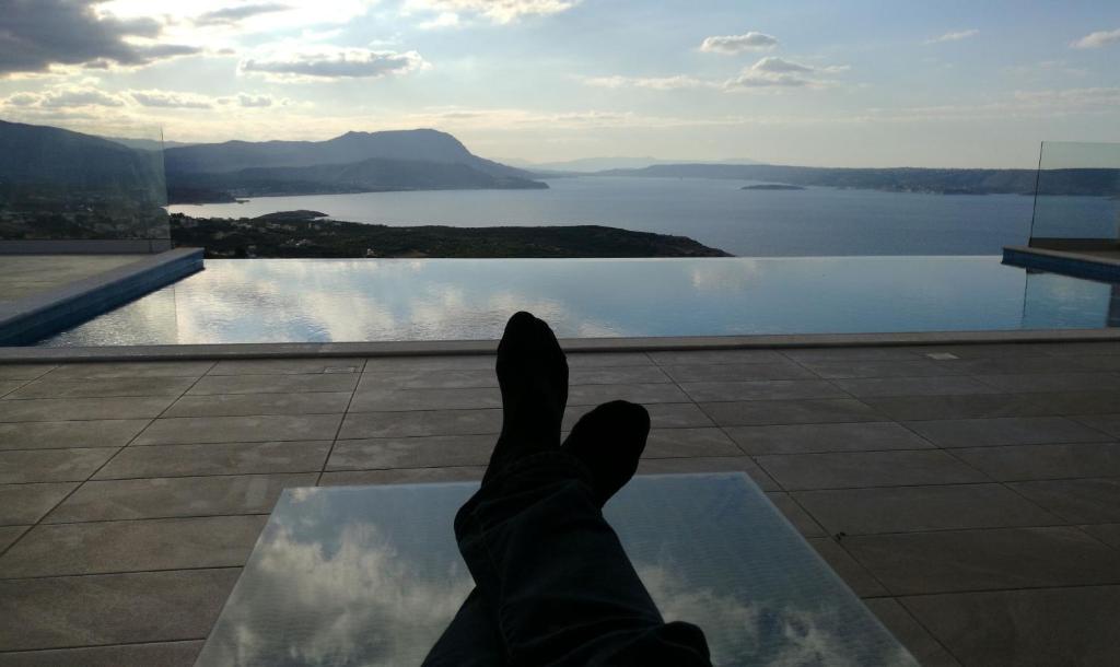 a persons feet on a table looking at a view of water at Villa Penelope in Kókkinon Khoríon