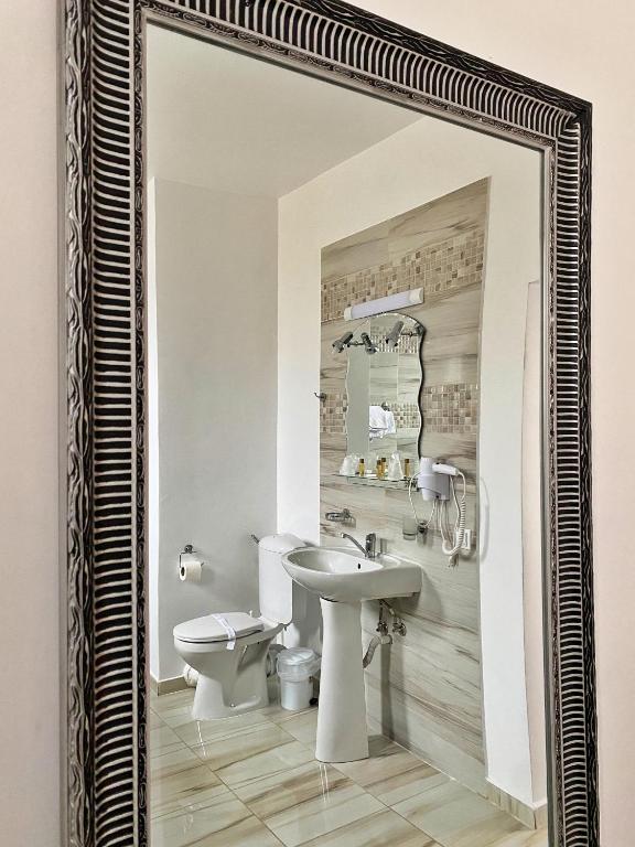 a mirror in a bathroom with a toilet and a sink at Hotel Belvedere in Piatra Neamţ