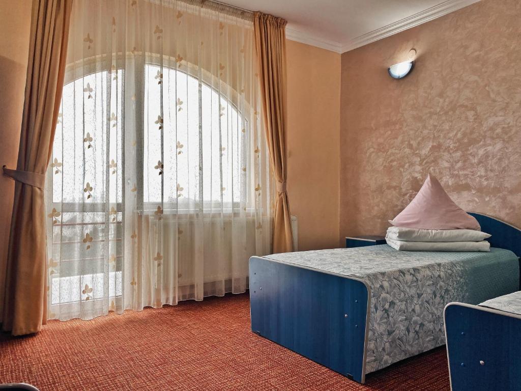 a bedroom with a bed and a large window at Hotel Belvedere in Piatra Neamţ