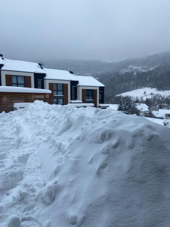 a pile of snow in front of a house at Górski Apartament Olimpijska 1L in Szczyrk