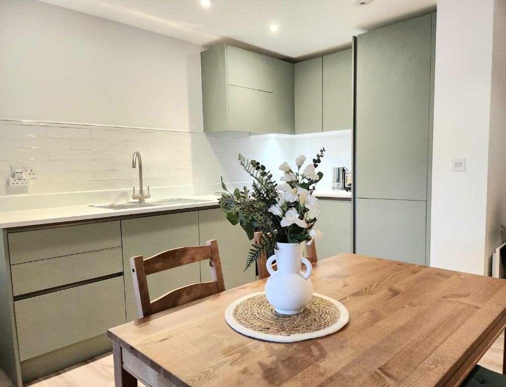 a vase of flowers on a wooden table in a kitchen at Lovely Luxury Apartment with Free Parking 209 in Luton