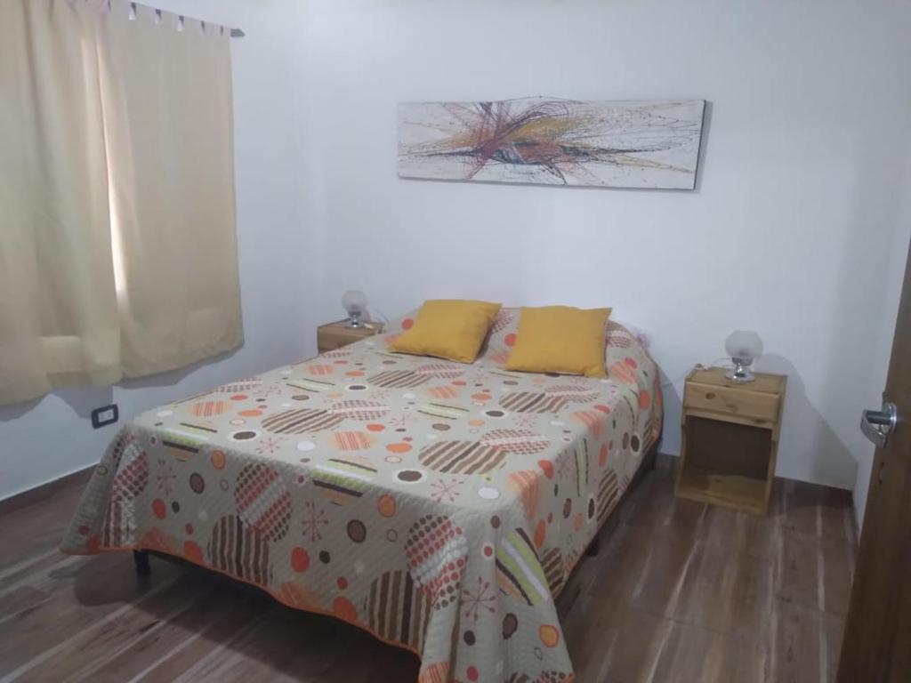 Un dormitorio con una cama con almohadas amarillas. en Cabaña Doña Alicia en San Rafael