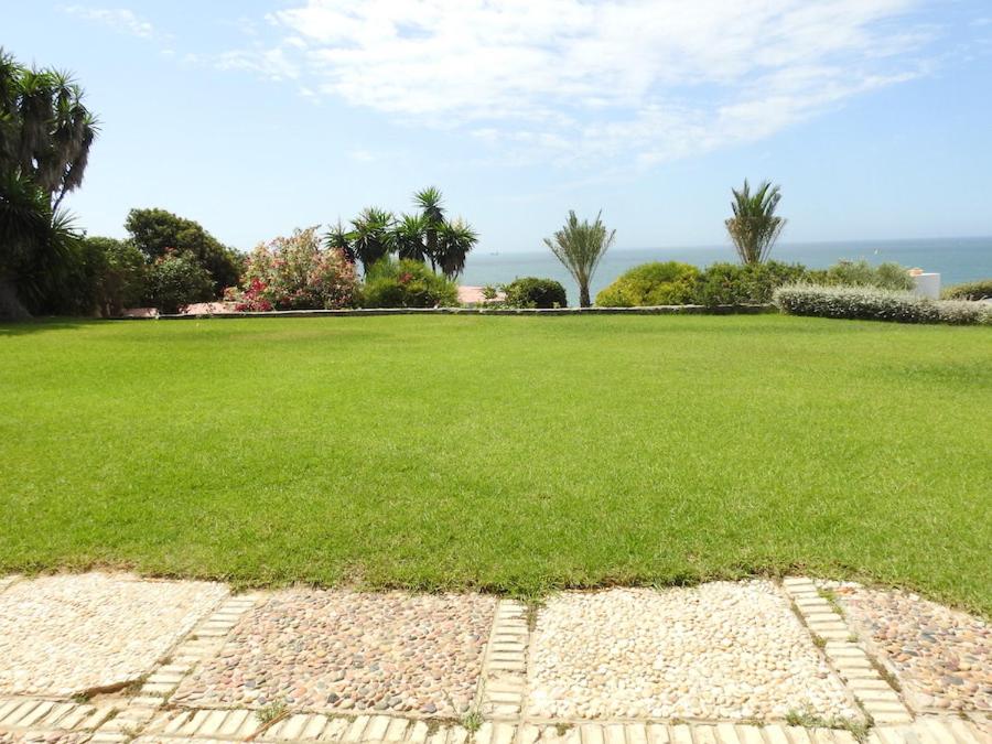un grand champ d'herbe verte avec l'océan en arrière-plan dans l'établissement Casa con vistas a la Bahía de Cádiz, à El Puerto de Santa María