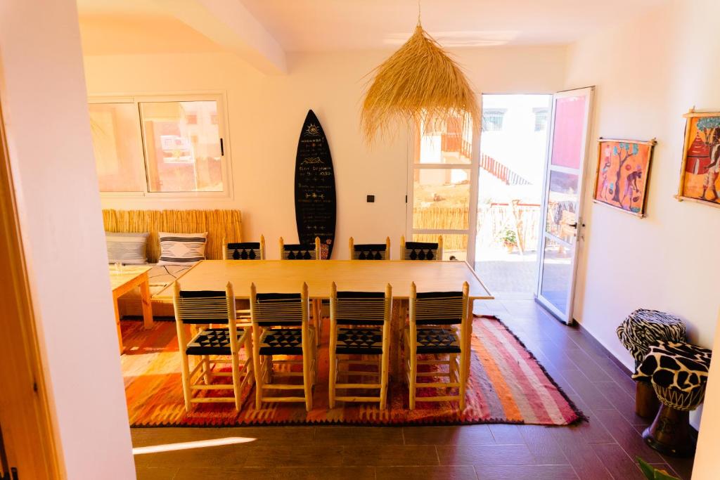 a dining room with a table and chairs and a surfboard at Dar Mouja, eco-friendly home in Imsouane