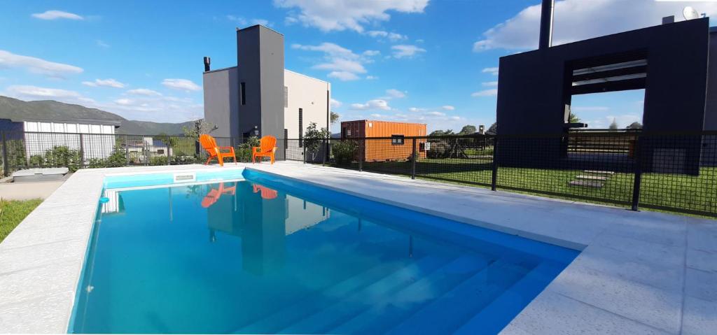 uma piscina com duas cadeiras laranja ao lado de um edifício em Cabañas Buena Vista - Santa Rosa em Santa Rosa de Calamuchita