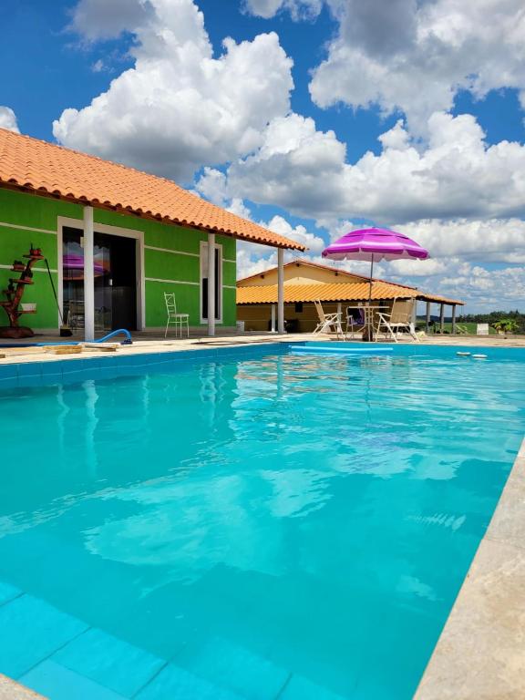 a swimming pool with a house and a purple umbrella at Pousada Sal da Terra in Carrancas