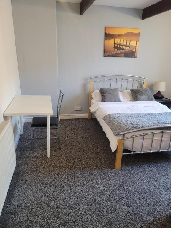 a bedroom with a bed and a table and a desk at No 2 Decent Home -Large Deluxe bedroom in Dukinfield