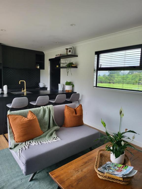 a living room with a couch and a table at Kotuku Cottage in Tauranga