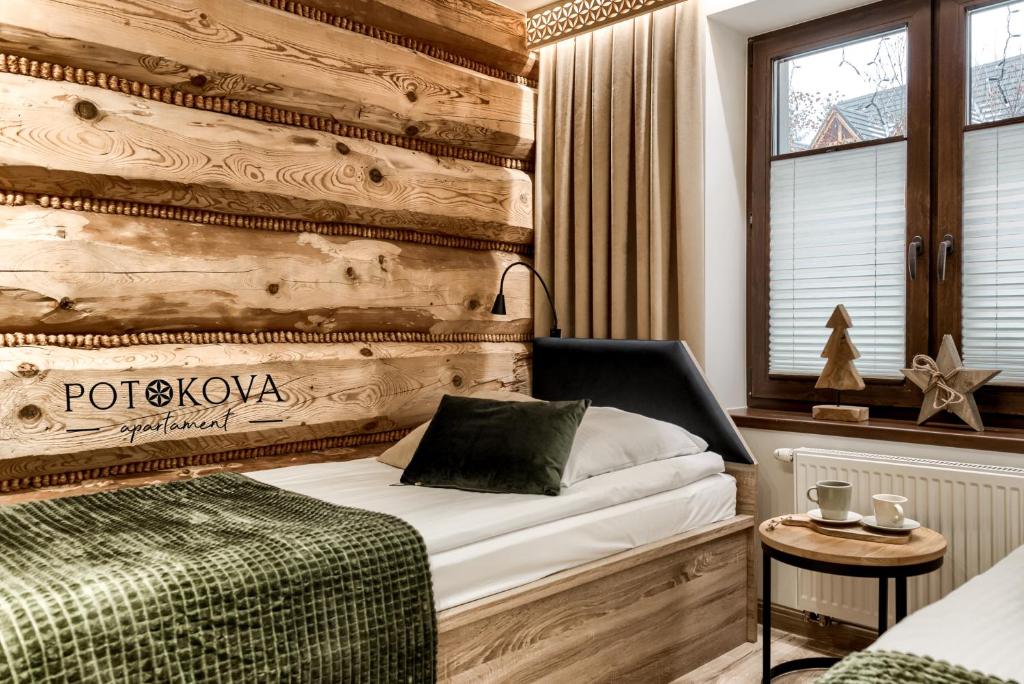 um quarto com uma cama e uma parede de madeira em Potokova apartament Centrum em Zakopane