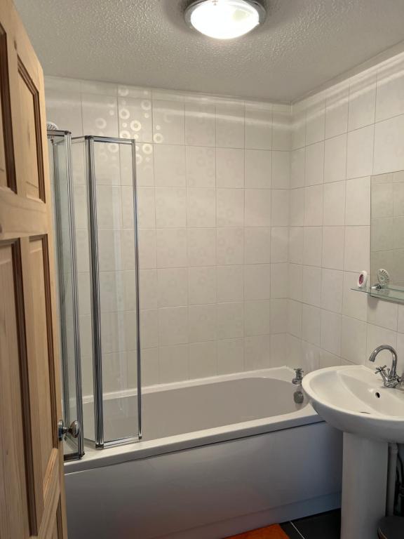 a bathroom with a bath tub and a sink at Home Away in Wigan
