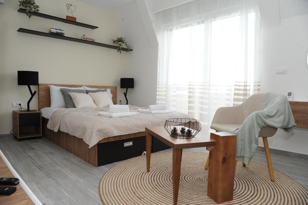 een slaapkamer met een bed, een tafel en een stoel bij Sunny Woods Apartment in Divčibare