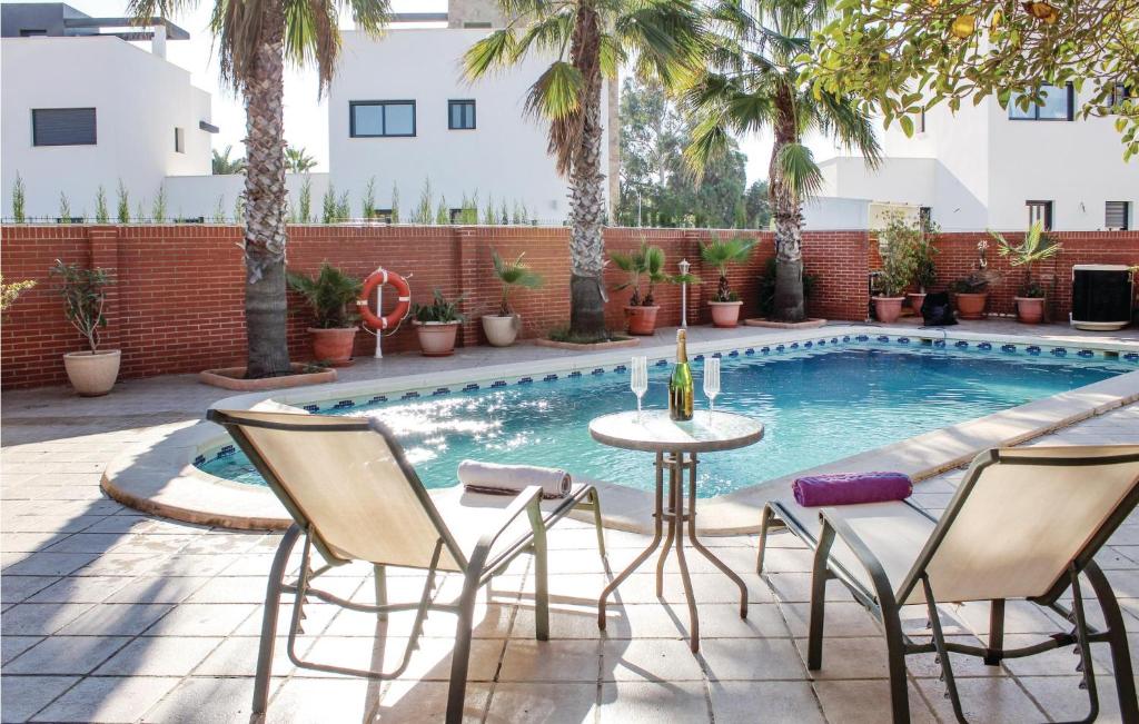 プラヤ・オンダにあるBeautiful Home In Playa Honda With Jacuzziのスイミングプールのそばにパティオ(テーブル、椅子付)
