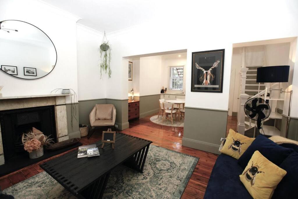 The Pavilion End - Central Paddington Apartment في سيدني: غرفة معيشة مع أريكة زرقاء ومدفأة