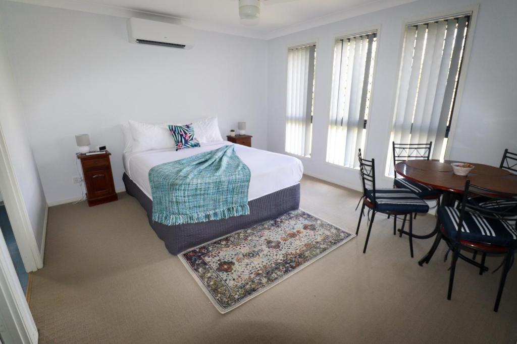 Schlafzimmer mit einem Bett, einem Tisch und Stühlen in der Unterkunft BLK Stays Guest House Deluxe Units Morayfield in Morayfield