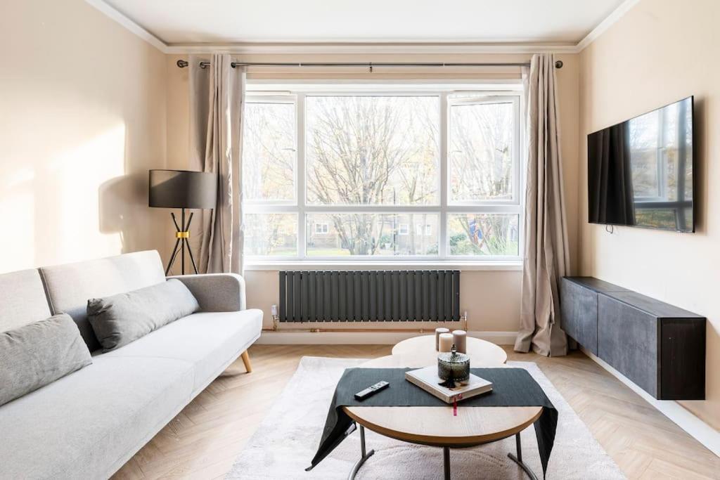 sala de estar con sofá blanco y ventana grande en Riverside serviced apartments, en Londres