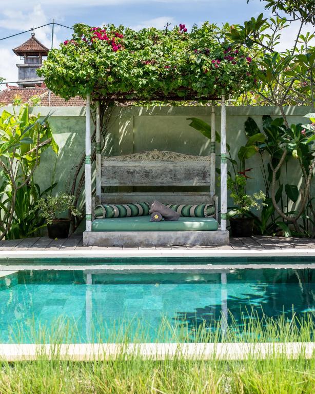 a bench with a pergola next to a swimming pool at Villa Kasih Lembongan in Nusa Lembongan
