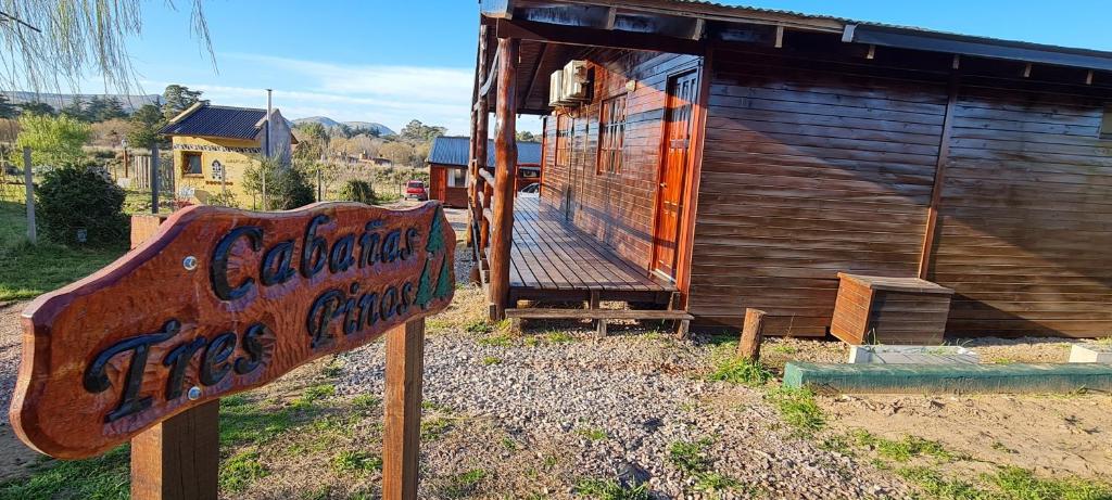 una señal frente a un edificio de madera en Cabañas Tres Pinos en Sierra de la Ventana