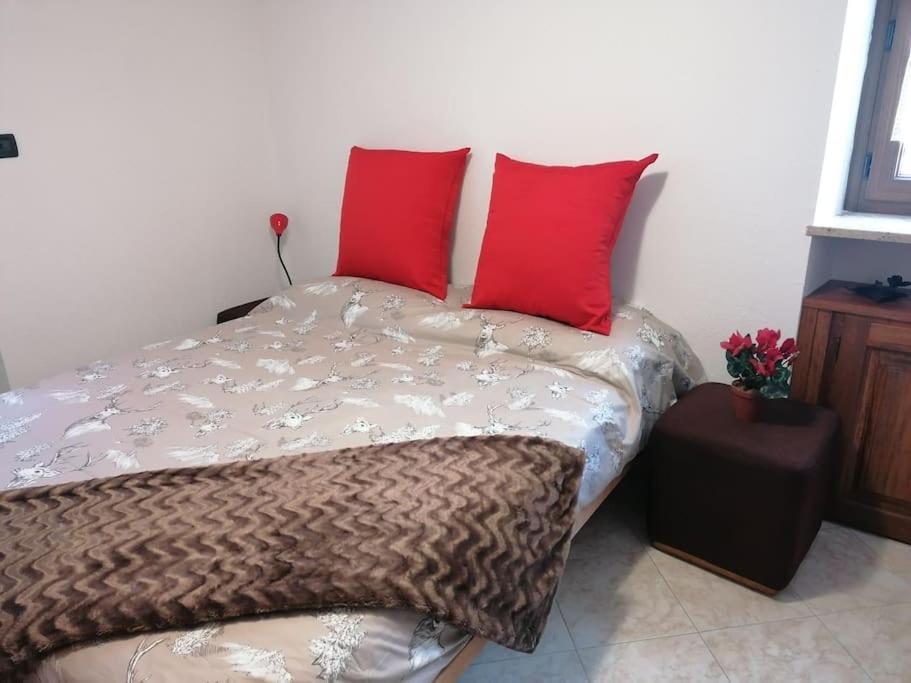 uma cama com duas almofadas vermelhas em cima em Chez Papi - A 5 min da piste da Sci e Stazione CIR VDA AO 0013 em Aosta