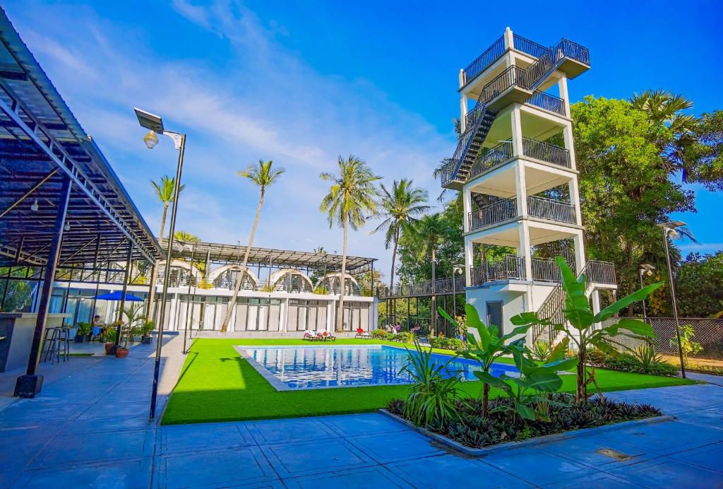 a building with a swimming pool and a tower at Adventure Dome Resort in Kep