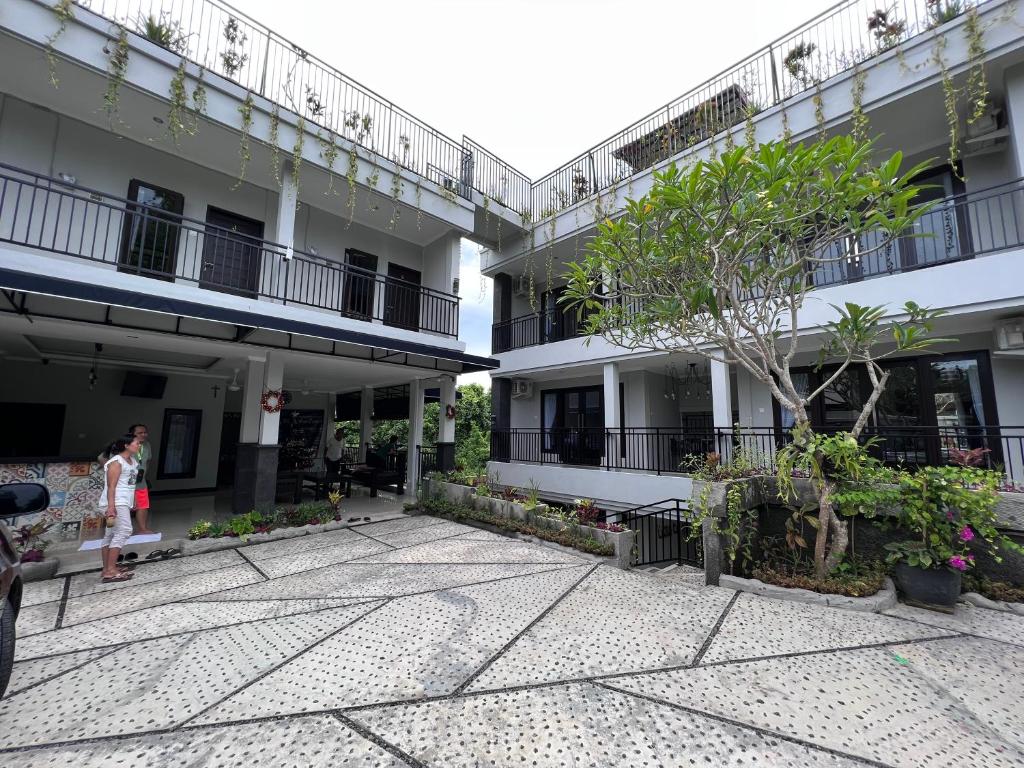a courtyard of a building with a tree in the middle at Green Hill Inn in Jimbaran