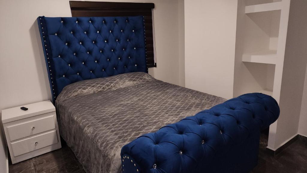 ein blaues getuftetes Bett in einem kleinen Schlafzimmer in der Unterkunft Departamentos vacacionales in Rosarito