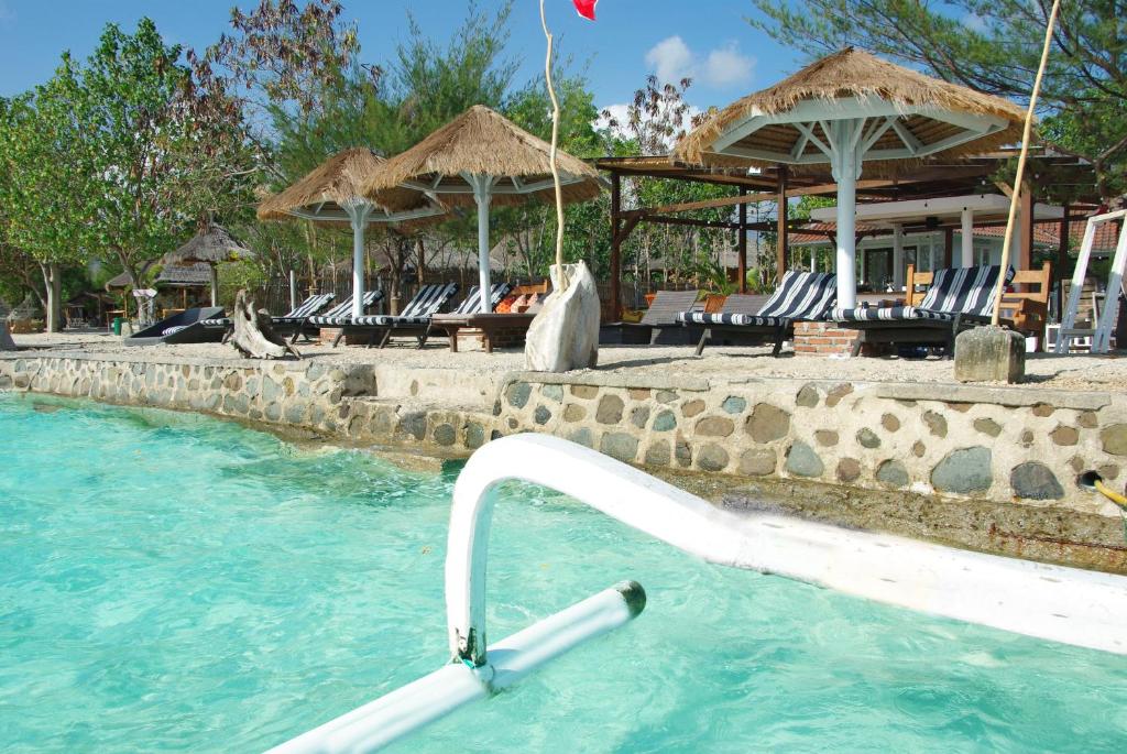 The High Dive Gili Gede by Ultimate Resorts في Gili Gede: مسبح المنتجع مع وجود كراسي وماء