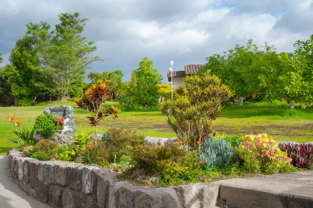 un jardín con flores en una pared de piedra en Hosteria Cananvalle, en Ibarra