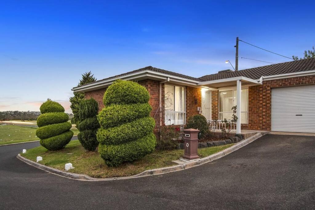 una casa con un arbusto delante de ella en Corner Cottage en Dandenong