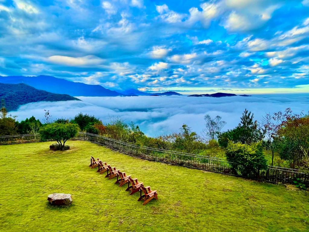 a group of benches sitting on a field with a view of clouds at Junyi Landscape Villa in Ren&#39;ai