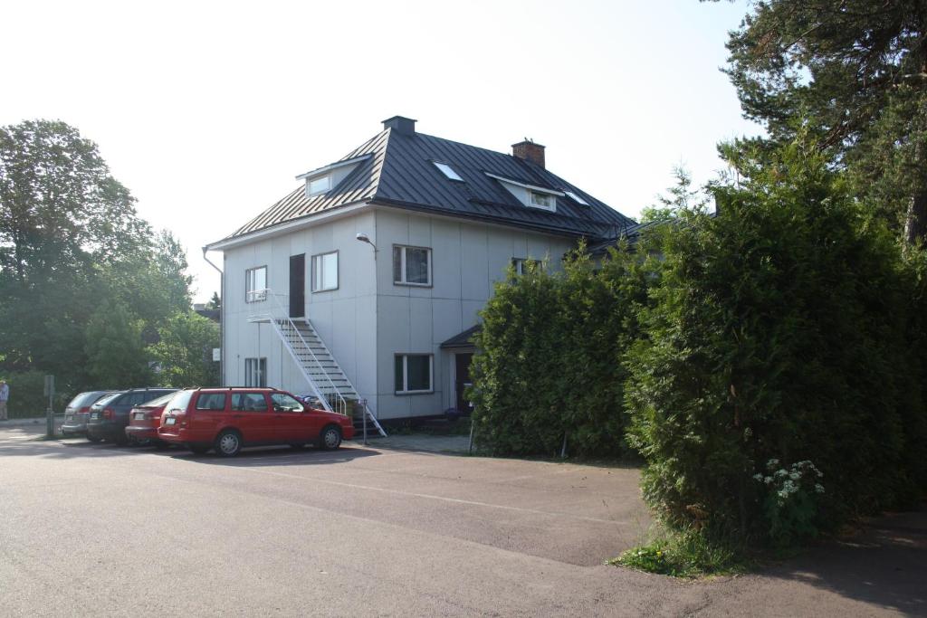 una gran casa blanca con coches aparcados en un aparcamiento en Gästhem Kronan, en Mariehamn