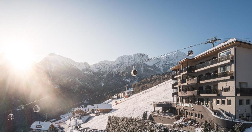 ein Skigebiet mit einer schneebedeckten Piste und einem Gebäude in der Unterkunft Kronplatz-Resort Hotel Kristall in Olang