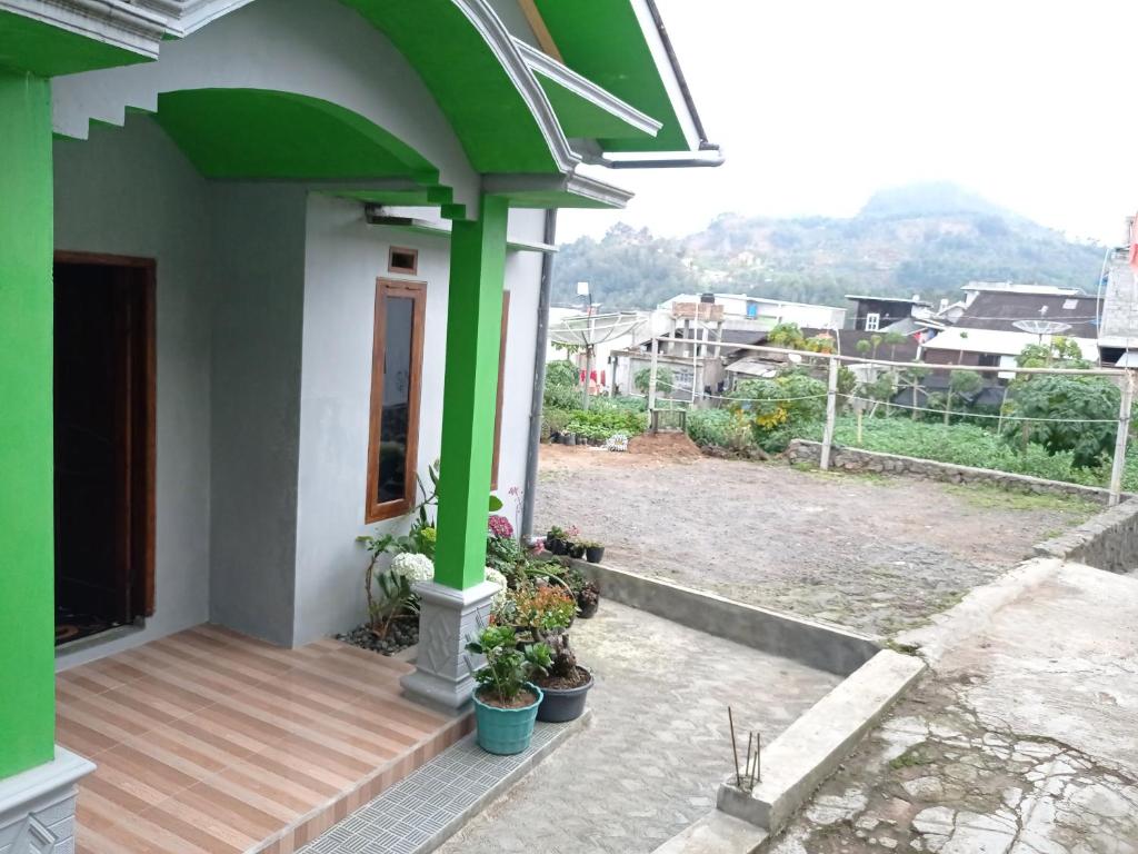 een huis met groene zuilen en een houten veranda bij Daratan Dieng in Diyeng