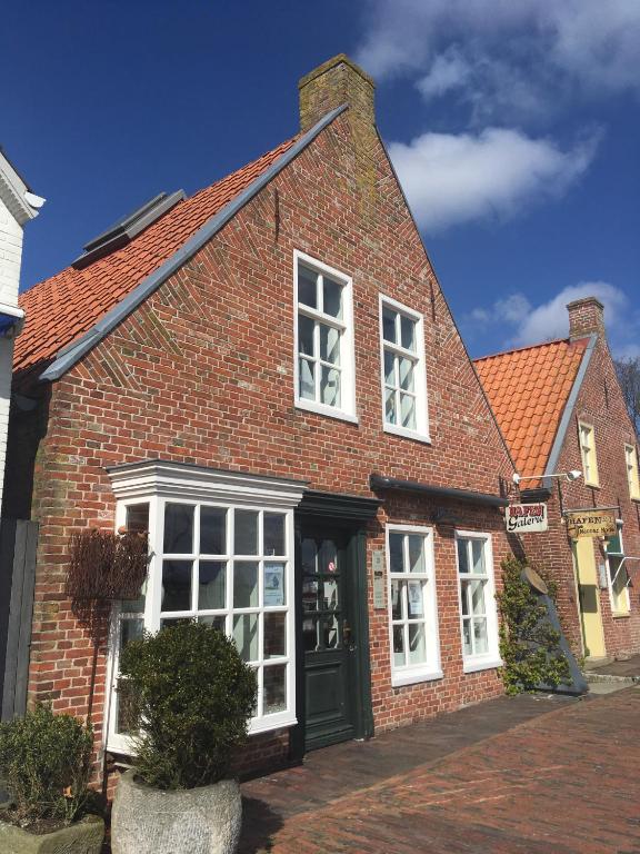 a brick house with a black door and white windows at Kapitänshaus mit Hafenblick in Greetsiel