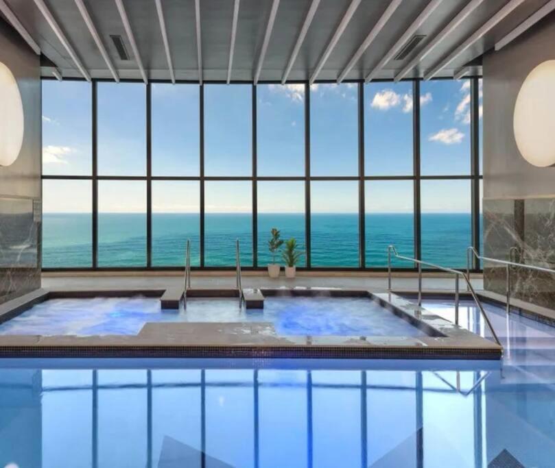 a large swimming pool with a view of the ocean at Surfers Paradise New Beachfront 2&3 BED APT in Gold Coast