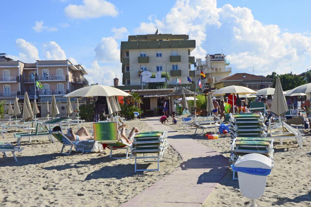 una playa de arena con sillas y sombrillas y un edificio en Hotel Colombo, en Rímini