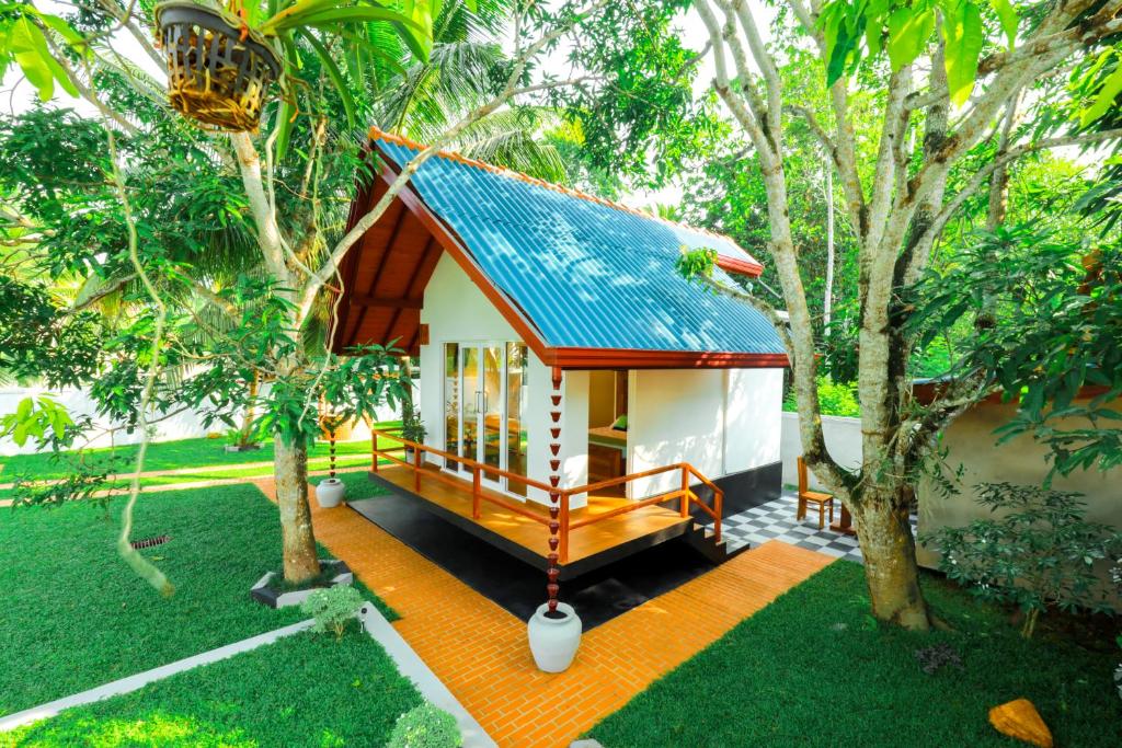 a small house with a blue roof in a garden at Kurumba Luxury Cabin in Ahangama