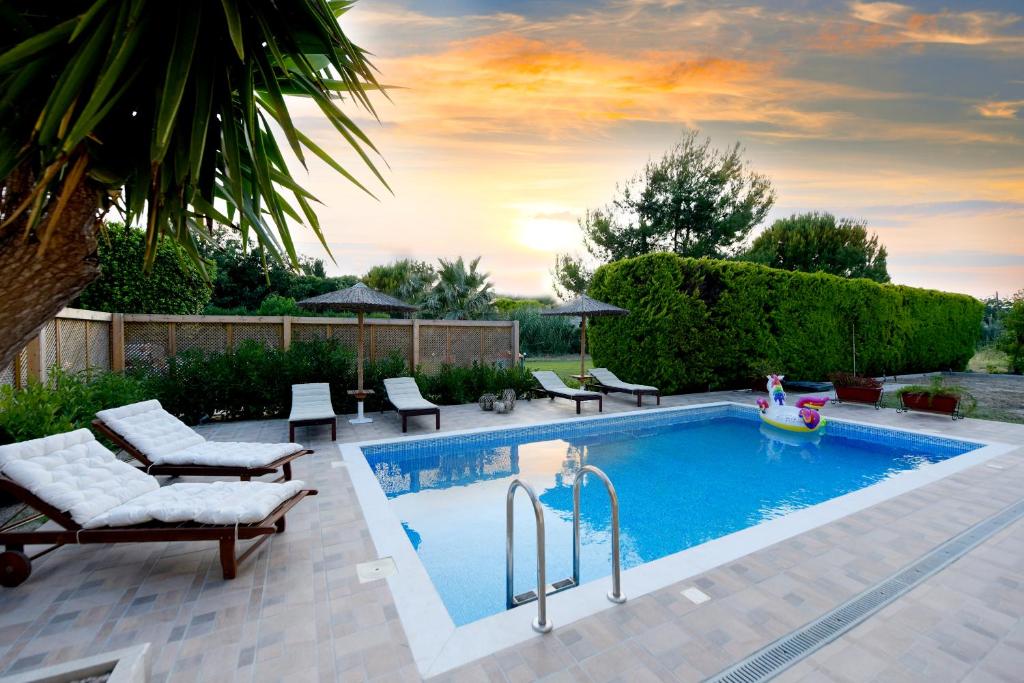 a swimming pool in a backyard with chairs and a table at Island Rodos Pool Suites in Ialysos
