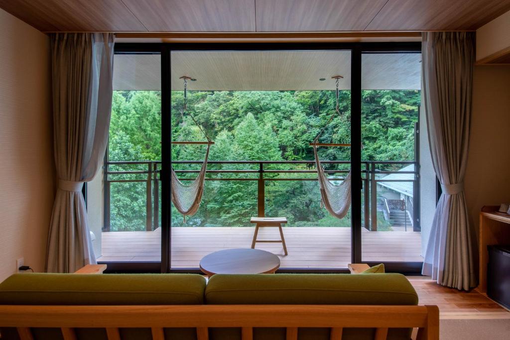 salon z zieloną kanapą przed dużym oknem w obiekcie Sakunami Onsen Yuzukushi Salon Ichinobo w mieście Sendai