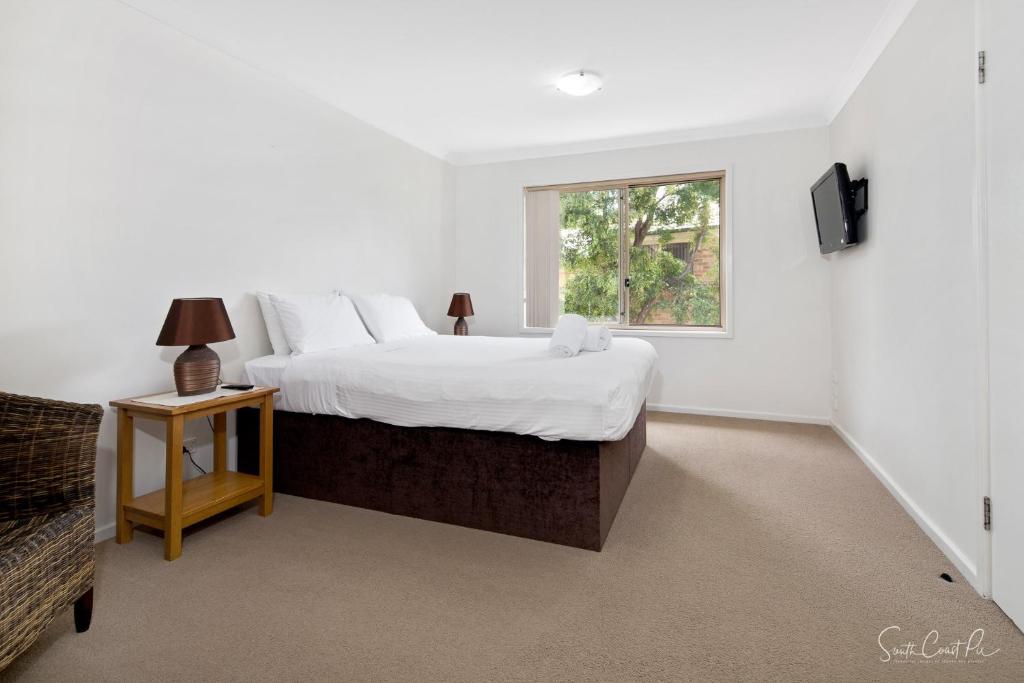 Un dormitorio con una cama grande y una ventana en Parker by the Sea, en Batemans Bay