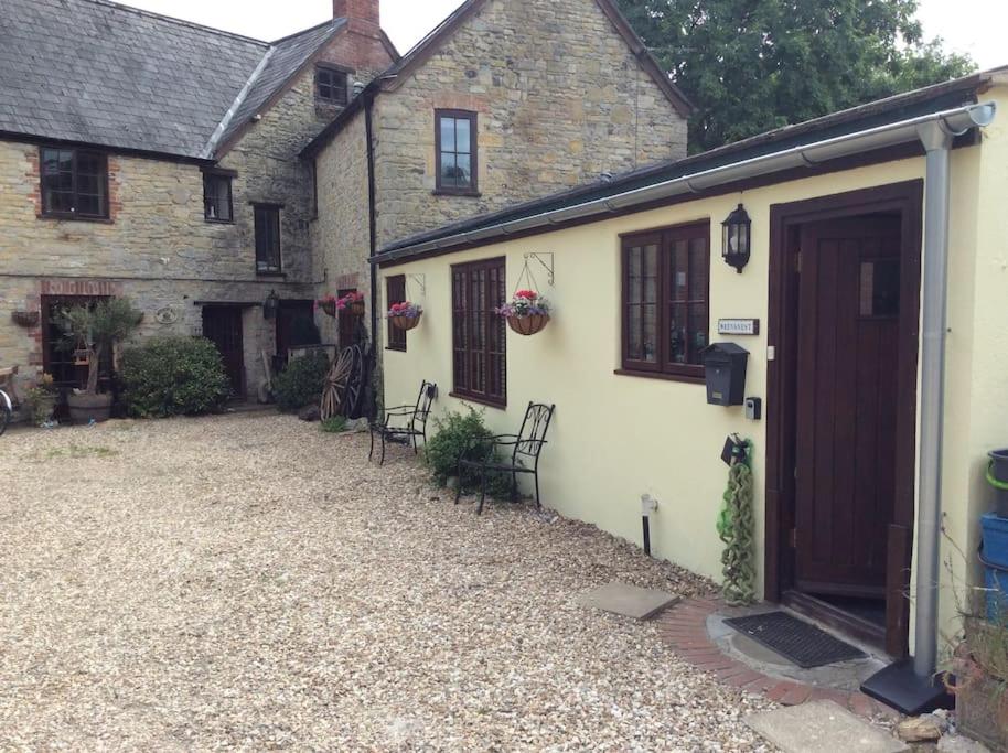 a house with a gravel driveway next to a garage at Wrens Nest in Axminster