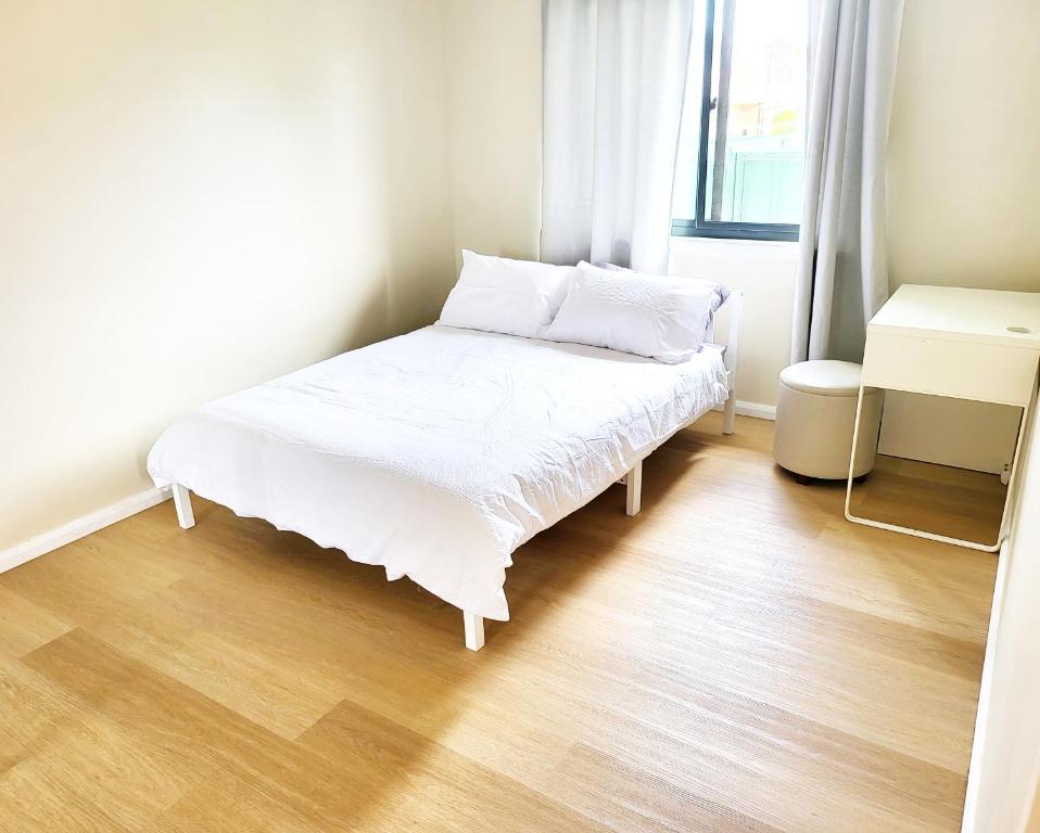 Cama blanca en habitación con suelo de madera en Kaban Power 7, en Doonside