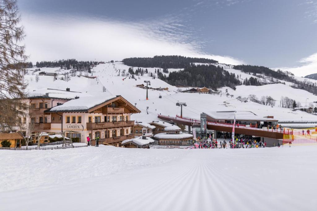 a ski resort with a group of people in the snow at Hotel Langeck in Maria Alm am Steinernen Meer