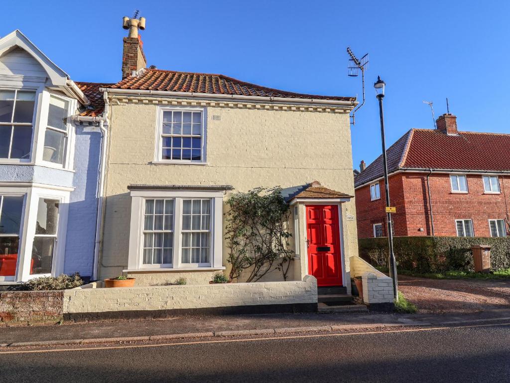 een huis met een rode deur in een straat bij Winkle Cottage, Aldeburgh in Aldeburgh