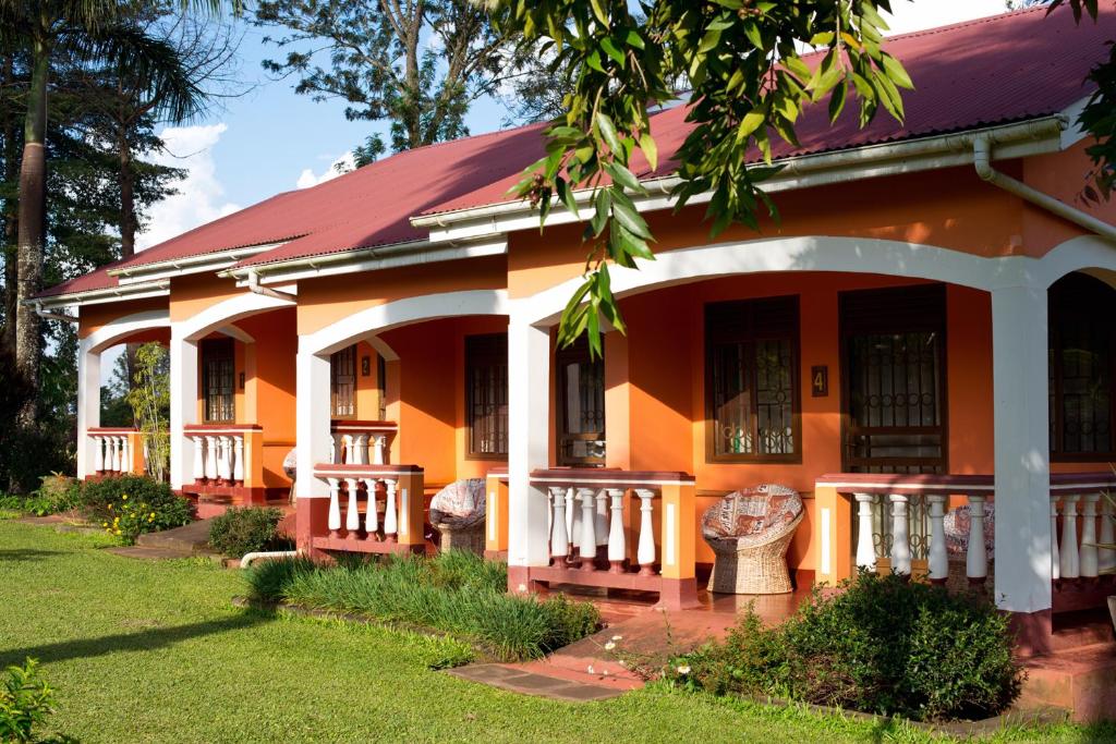pomarańczowy dom z czerwonym dachem w obiekcie Kluges Guest Farm w mieście Kibale