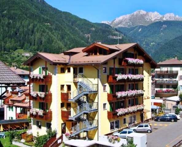 ein gelbes Apartmenthaus mit Balkon und Parkplatz in der Unterkunft Sport Hotel Sass Maor in Predazzo