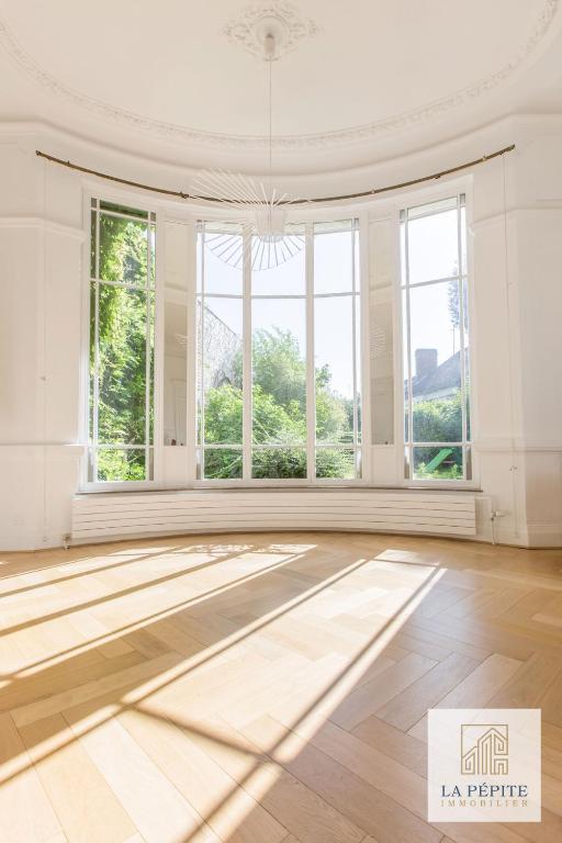 Habitación vacía con ventanas grandes y suelo de madera. en Hôtel particulier - Le 119, en Valenciennes