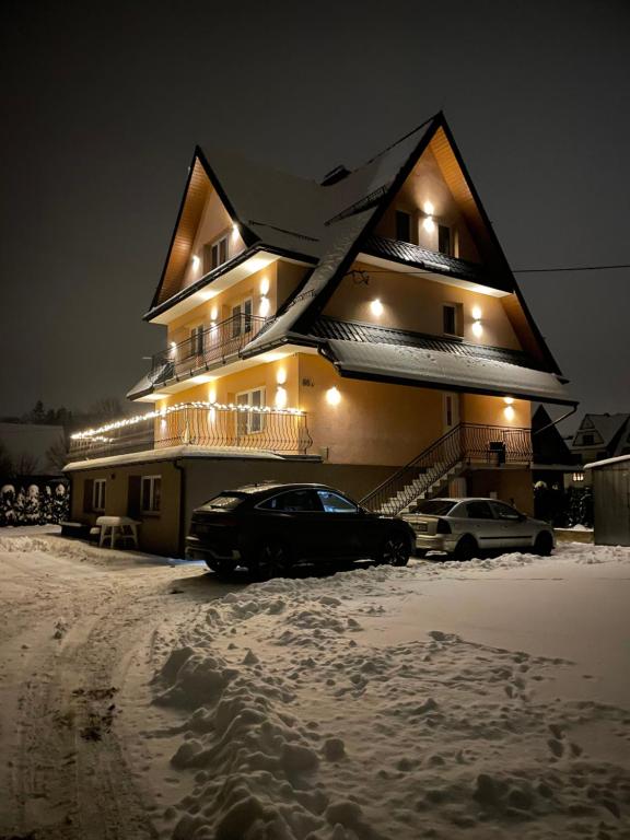 a house with cars parked in the snow at night at Pokoje Gościnne Letycja in Biały Dunajec