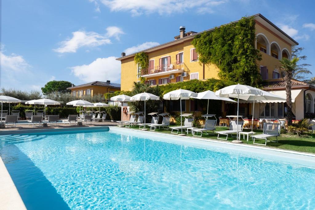uma piscina com cadeiras e guarda-sóis em frente a um edifício em La Quiete Park Hotel em Manerba del Garda