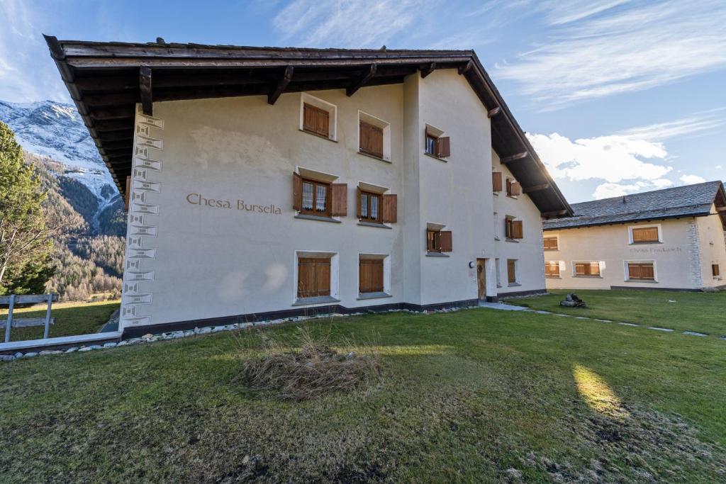 a large white building with a grass yard at Chesa Bursella - Madulain in Madulain