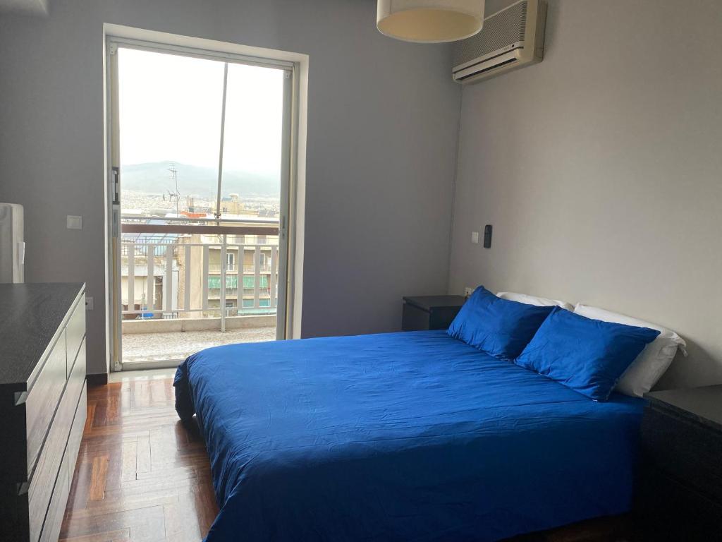 a bedroom with a blue bed and a large window at Elegant City Flat in Athens